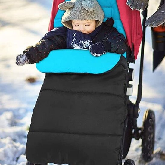Bébé bien au chaud dans une chancelière bébé noire et bleu turquoise, idéale pour les promenades en hiver.