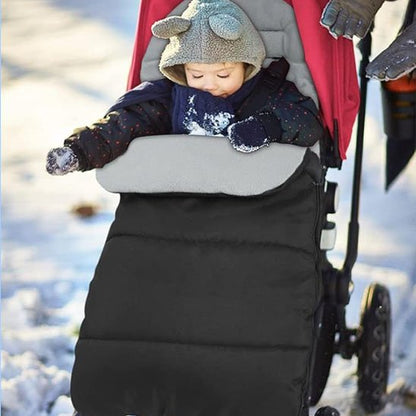 Bébé emmitouflé dans une chancelière bébé noire pendant une promenade hivernale dans la neige.