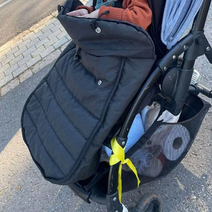 Poussette avec espace de rangement équipée d'une chancelière noire, offrant confort et protection au bébé.