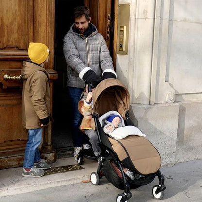 Parents en promenade avec leur poussette équipée d'une chancelière bébé chaude pour hiver.
