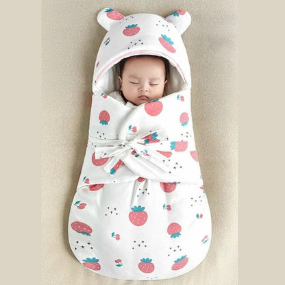 Bébé endormi dans un nid d'ange à motif (fraises) rouge, avec capuche à oreilles et intérieur doux.