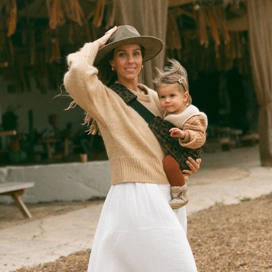 Maman au style bohème portant son bébé avec une écharpe de portage bébé confortable et élégante
