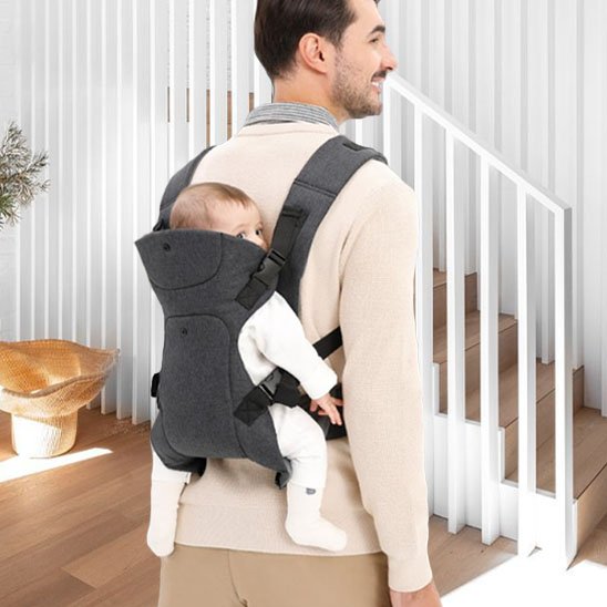 Papa portant son bébé dans le dos avec un porte-bébé ergonomique de couleur gris fonce assurant sécurité et confort.