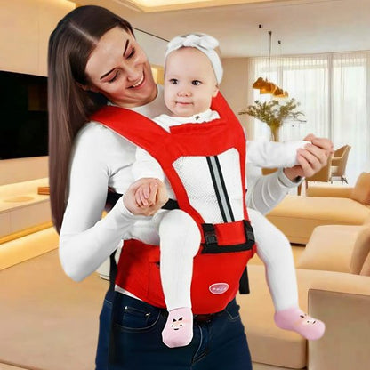 Maman dans le salon heureuse portant son bébé face avant dans un porte-bébé ergonomique rouge, conçu pour un confort optimal.
