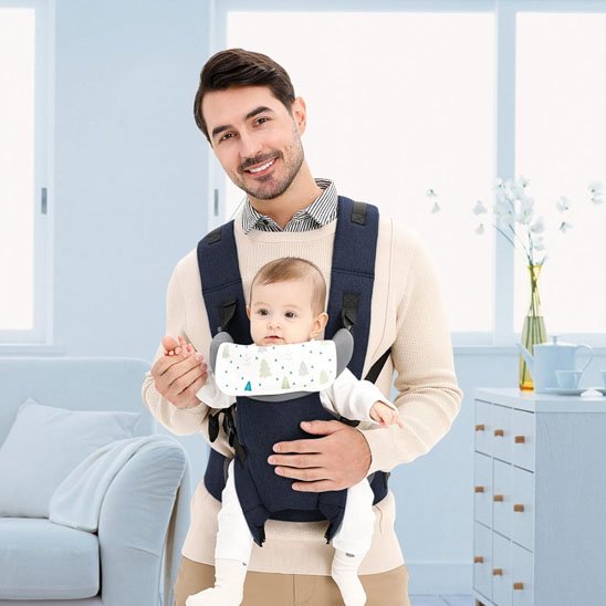 Papa portant son bébé face avant dans un porte-bébé ergonomique couleur gris fonce, parfait pour le confort