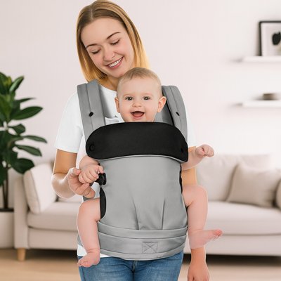 Porte-bébé physiologique gris avec maman et bébé souriants à la maison, maintien parfait et design moderne.