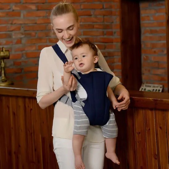 Maman tenant son bébé dans un porte-bébé bleu ergonomique, parfait pour un bon maintien.