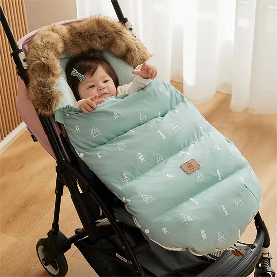 Bébé confortablement installe dans une poussette avec chancelière vert menthe pour les promenades hivernales