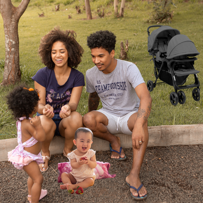 Famille souriante assise avec deux enfants pendant une promenade au parc.