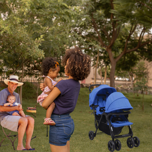 Les parents tenant leurs bébés près d'une poussette double bleue dans un parc ensoleillé.