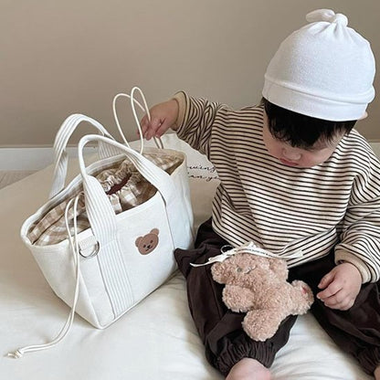Bébé assis avec un sac à langer blanc et une peluche