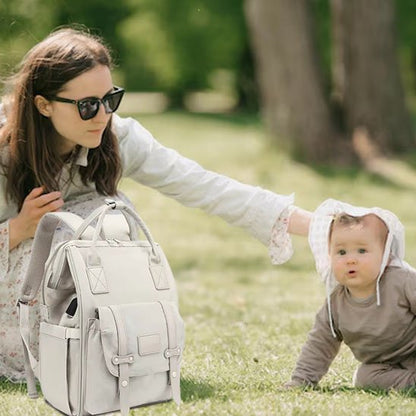 Maman assise dans l'herbe avec son bébé et un sac à langer beige