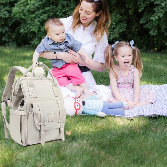 Sac à langer beige posé sur une couverture de pique-nique avec maman et enfants