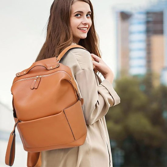 Femme souriante portant un sac camel élégant