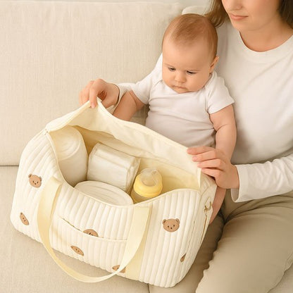 Maman ouvrant un sac à langer crème avec bébé assis à côté