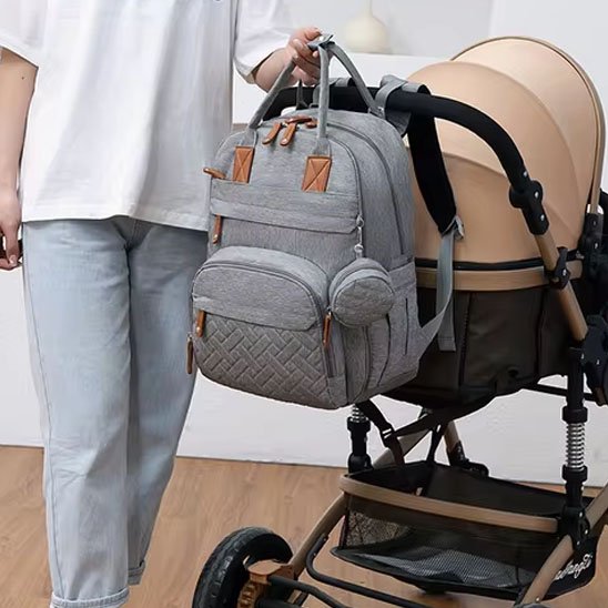 Sac à langer gris accroché à une poussette bébé