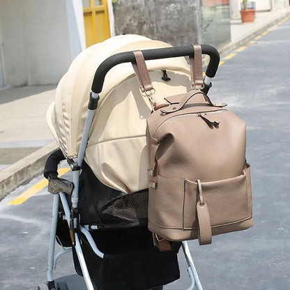 Sac à langer marron accroché à une poussette bébé